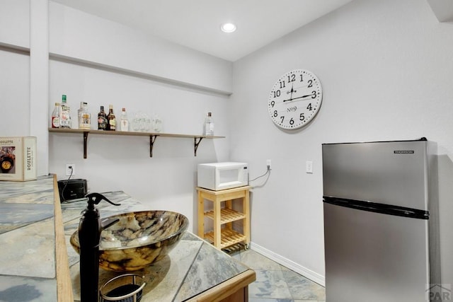 interior space featuring open shelves, recessed lighting, white microwave, freestanding refrigerator, and baseboards