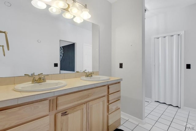 bathroom with tile patterned flooring, a sink, baseboards, and double vanity