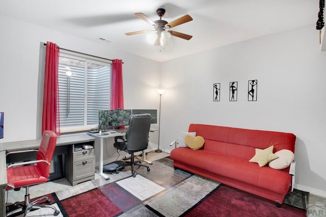 office space with visible vents, a ceiling fan, and baseboards