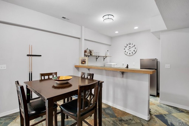 dining area with stone finish flooring, recessed lighting, visible vents, and baseboards