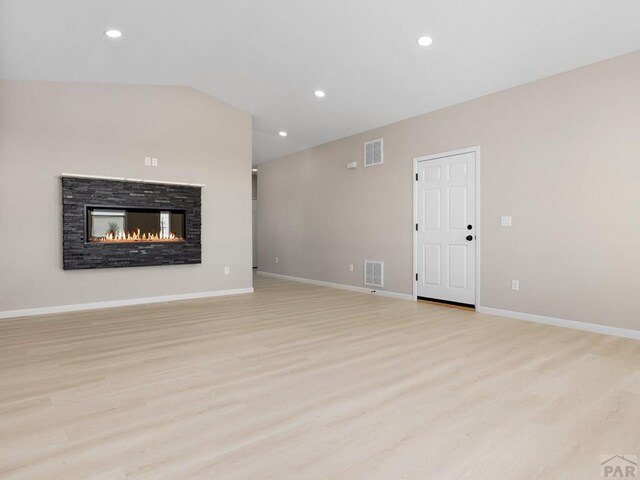 unfurnished living room featuring light wood-style flooring, visible vents, vaulted ceiling, and baseboards