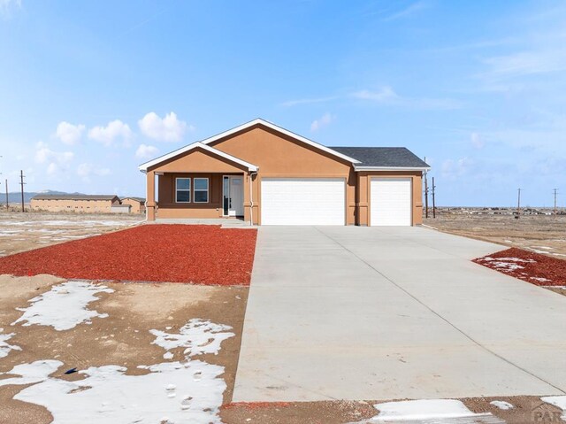 ranch-style house featuring concrete driveway, an attached garage, and stucco siding