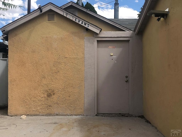 1905 E Evans Ave, Pueblo, CO 81004 - doorway to property featuring stucco siding and a shingled roof