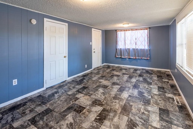 unfurnished room with crown molding, baseboards, and a textured ceiling