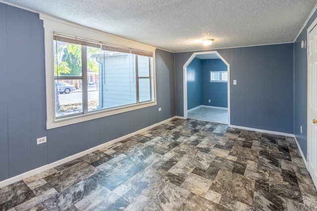 bonus room featuring arched walkways, a textured ceiling, and baseboards