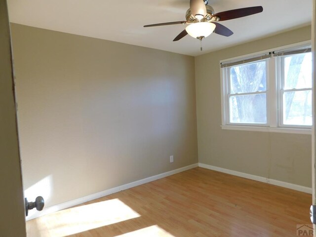 empty room with light wood finished floors, baseboards, and a ceiling fan