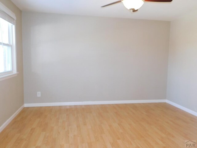 empty room featuring ceiling fan, light wood-type flooring, and baseboards