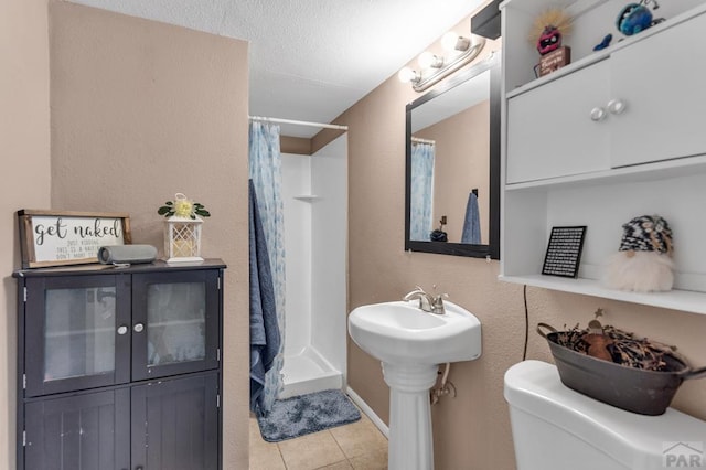 bathroom featuring toilet, a shower stall, a sink, and tile patterned floors