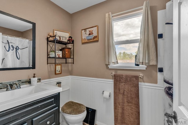 bathroom featuring toilet, a wainscoted wall, and vanity