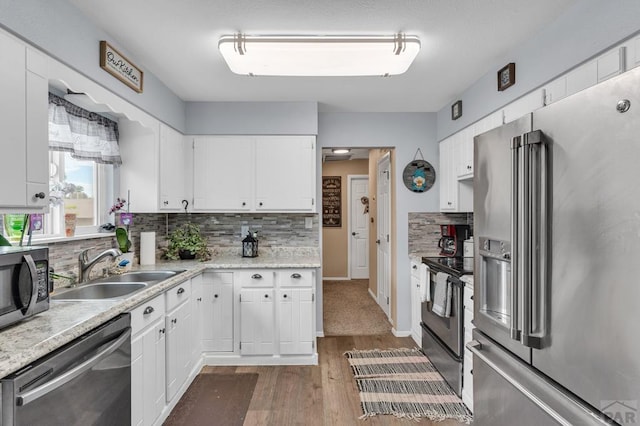 kitchen featuring stainless steel appliances, a sink, white cabinetry, light countertops, and backsplash