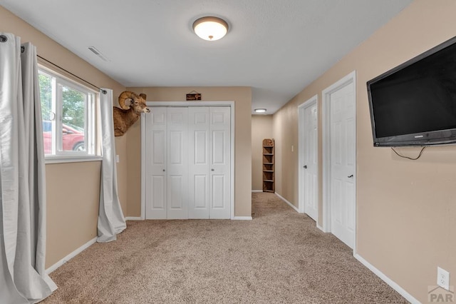 unfurnished bedroom featuring baseboards, a closet, visible vents, and light colored carpet