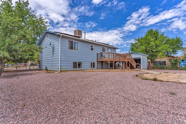 back of property with fence, a wooden deck, and stairs