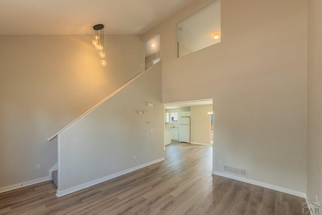 unfurnished living room featuring stairway, wood finished floors, and visible vents