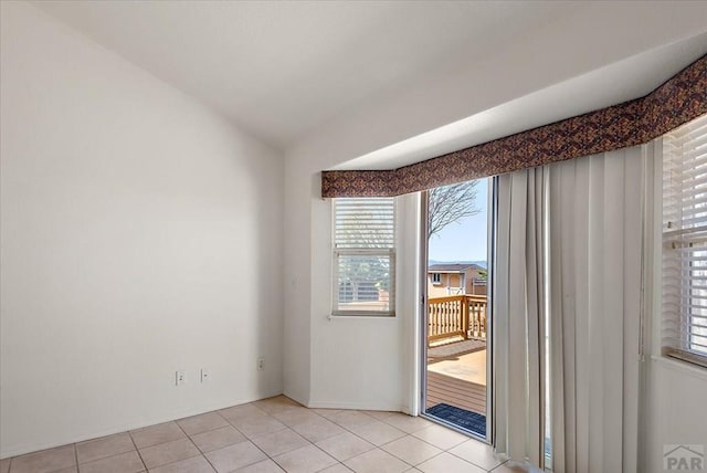 empty room with vaulted ceiling and light tile patterned floors