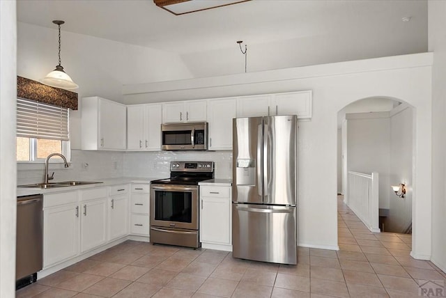 kitchen featuring lofted ceiling, a sink, decorative backsplash, light countertops, and appliances with stainless steel finishes