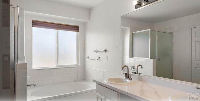 bathroom with tasteful backsplash, a garden tub, double vanity, a stall shower, and a sink