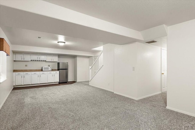 interior space with stairway, baseboards, visible vents, a textured ceiling, and dark carpet