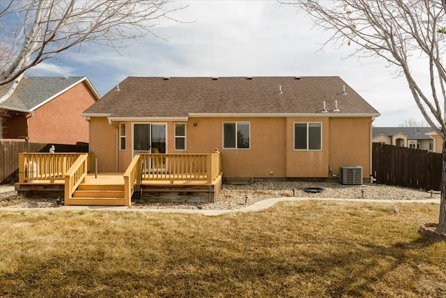 back of property with stucco siding, central AC unit, and fence