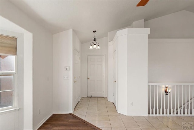 hall featuring vaulted ceiling, a notable chandelier, plenty of natural light, and tile patterned floors