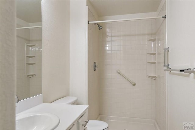 bathroom featuring toilet, a stall shower, and vanity