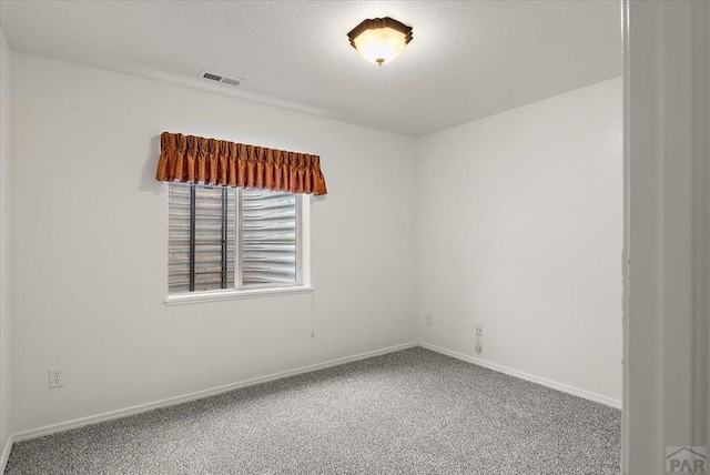 carpeted spare room with visible vents and baseboards