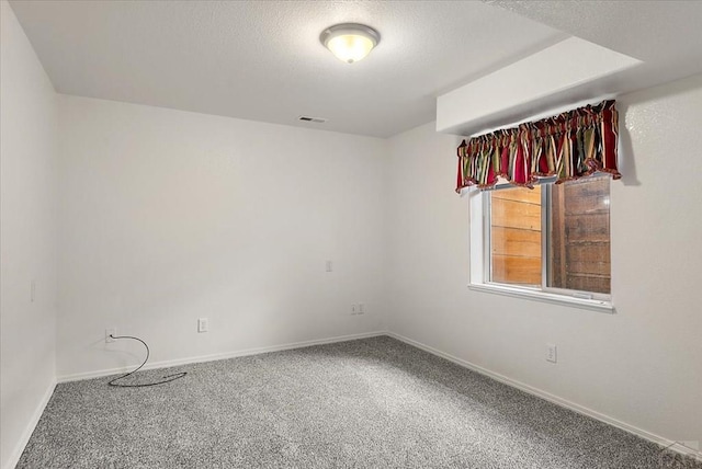 carpeted empty room featuring baseboards, visible vents, and a textured ceiling