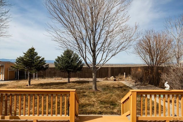 view of yard with a wooden deck, an outbuilding, and a fenced backyard