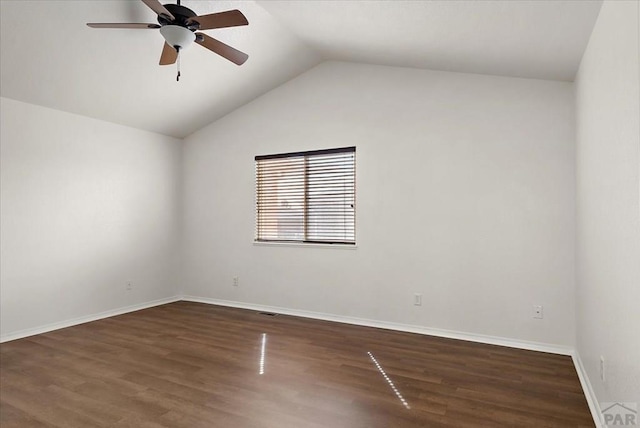 empty room with a ceiling fan, vaulted ceiling, wood finished floors, and baseboards