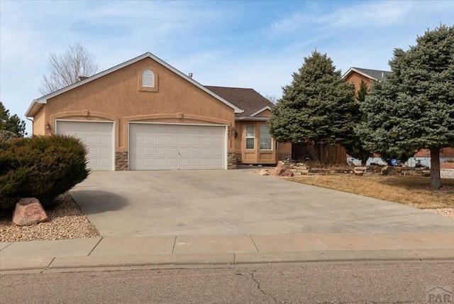 view of front facade with stone siding, stucco siding, an attached garage, and driveway