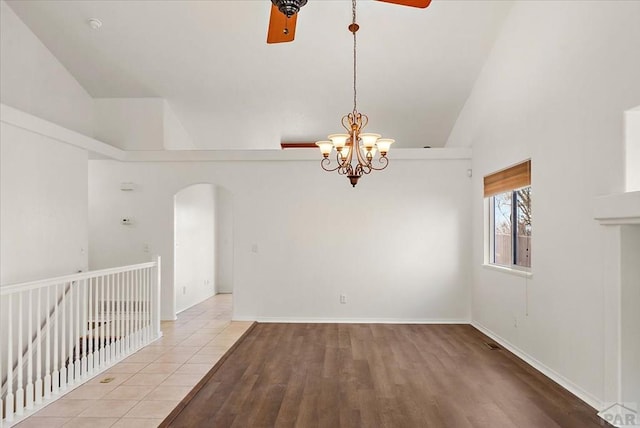 unfurnished room with arched walkways, baseboards, lofted ceiling, and wood finished floors