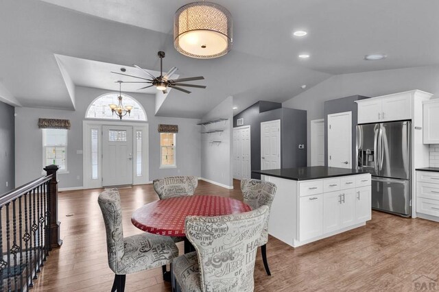 dining space with lofted ceiling, light wood-style flooring, recessed lighting, baseboards, and an inviting chandelier