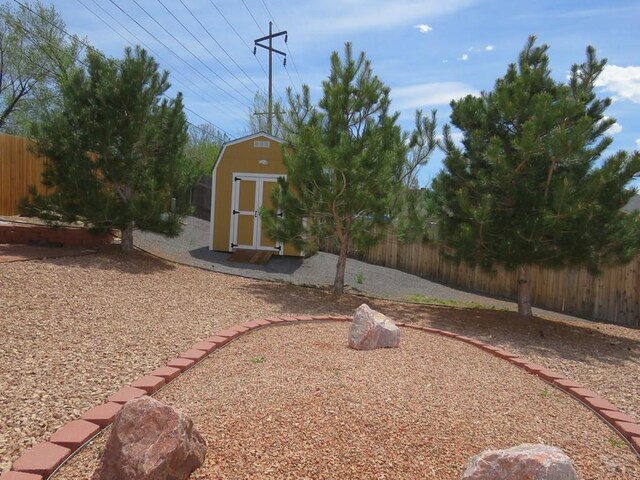 view of yard featuring a shed, an outdoor structure, and fence