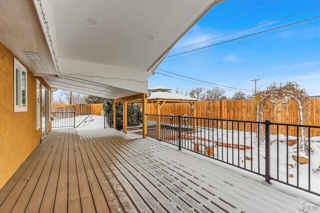 snow covered deck featuring a gazebo and fence