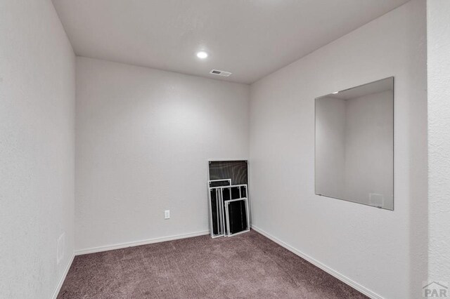 carpeted spare room featuring visible vents and baseboards