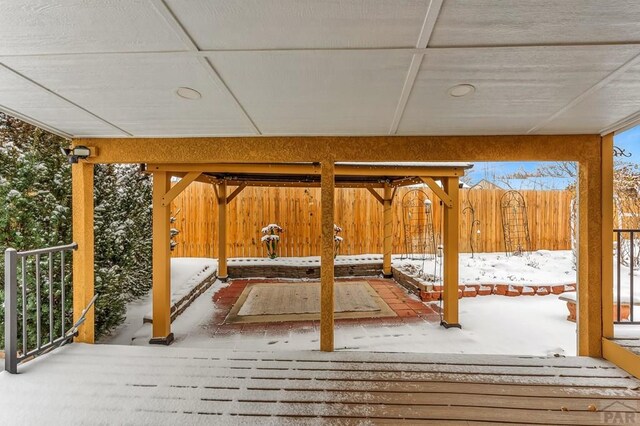 snow covered deck featuring fence