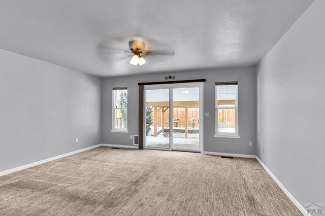 carpeted empty room with visible vents, baseboards, and ceiling fan