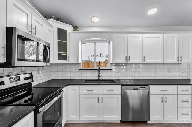 kitchen with stainless steel appliances, dark countertops, and white cabinets