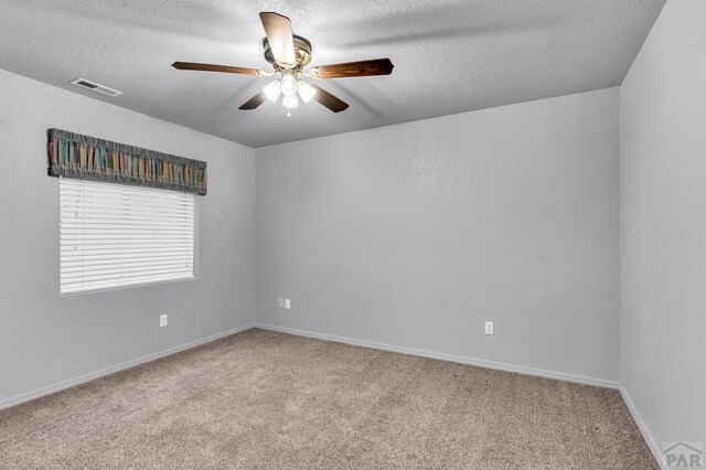 empty room with a textured ceiling, light carpet, visible vents, a ceiling fan, and baseboards