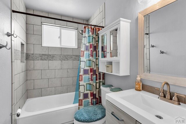 bathroom featuring toilet, shower / tub combo with curtain, and vanity