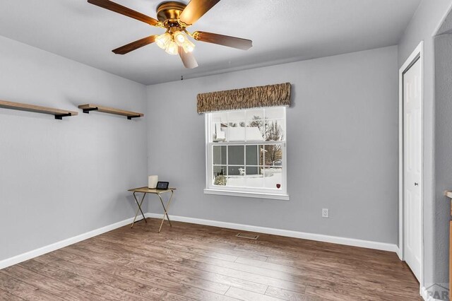 empty room featuring baseboards, visible vents, ceiling fan, and wood finished floors