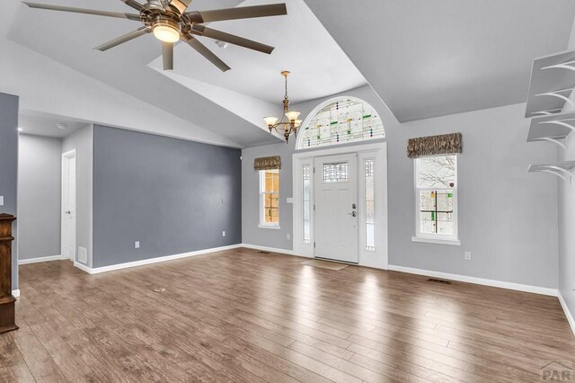 entrance foyer featuring lofted ceiling, baseboards, wood finished floors, and ceiling fan with notable chandelier