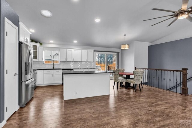 kitchen featuring stainless steel fridge, dark countertops, glass insert cabinets, hanging light fixtures, and white cabinetry