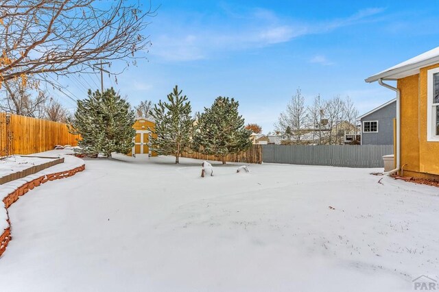 snowy yard with a fenced backyard