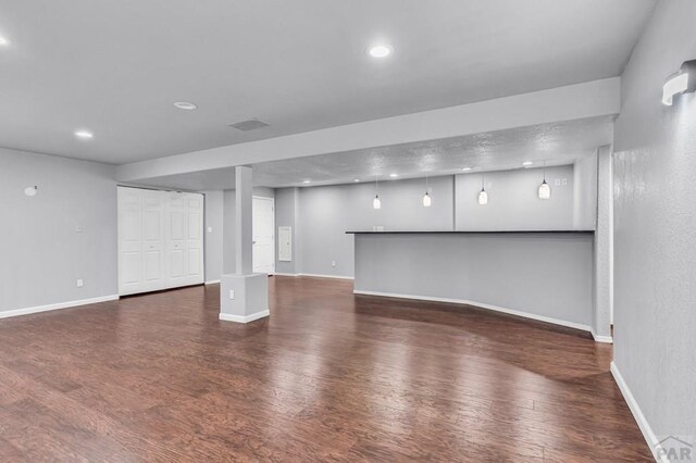 below grade area with dark wood-type flooring, recessed lighting, and baseboards