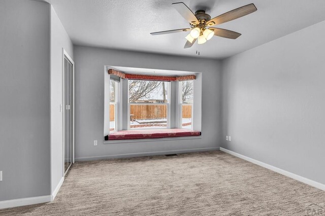 empty room with a ceiling fan, light carpet, and baseboards