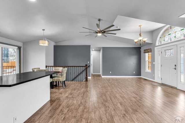 entrance foyer featuring dark wood-style floors, lofted ceiling, baseboards, and ceiling fan with notable chandelier