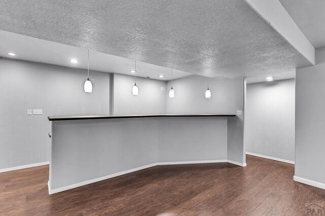 interior space featuring recessed lighting, dark wood-style flooring, a textured ceiling, and baseboards