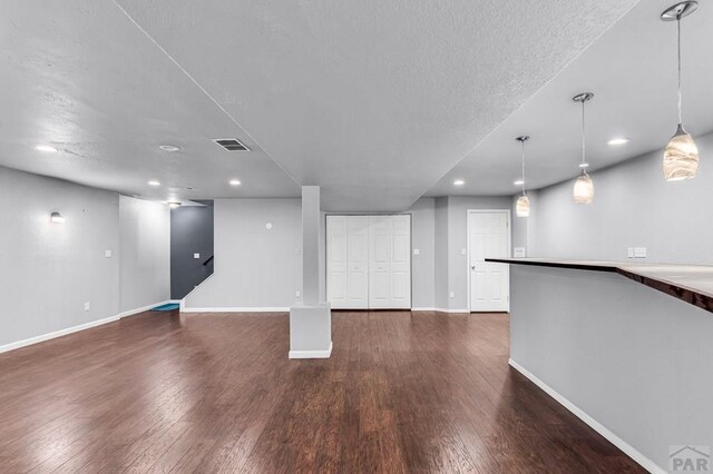 interior space with baseboards, visible vents, dark wood finished floors, and a textured ceiling