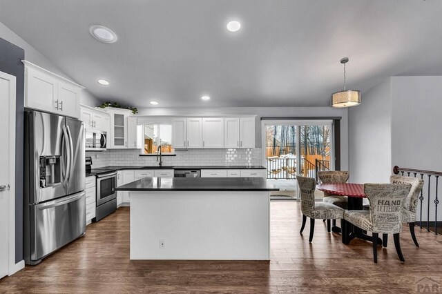 kitchen featuring hanging light fixtures, appliances with stainless steel finishes, dark countertops, and white cabinets