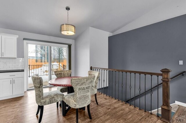 dining space with vaulted ceiling and wood finished floors